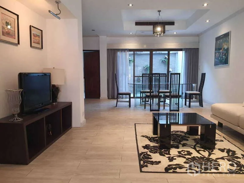 Townhouse for rent in Khlong Toei, Bangkok - Repeat view of open living and dining area with TV console and glass dining set.