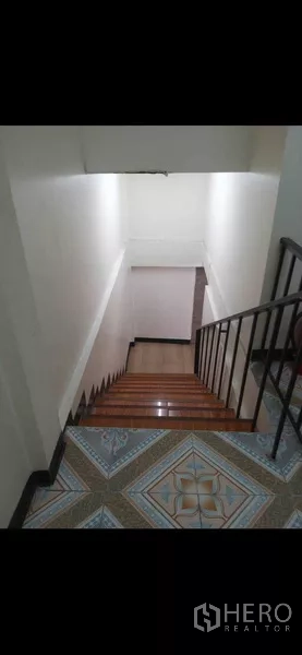 Shophouse for rent or sale in Phra Khanong, Bangkok - Wooden staircase with metal handrail descending to the lower floor in the shophouse.