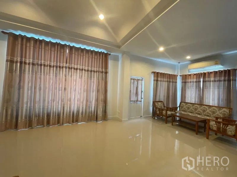 Detached House for sale in Lat Krabang, Bangkok - Bright living room with glossy tile floors, recessed lighting, curtains and an air conditioner.
