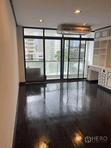 Condominium for rent or sale in Watthana, Bangkok - Room with wall-to-wall windows, built-in desk and access to balcony.