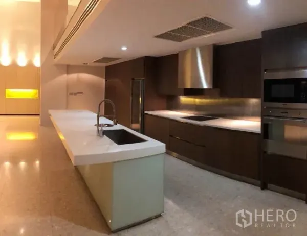 Condominium for sale in Khlong Toei, Bangkok - Gourmet kitchen with long island, dark wood cabinetry, built-in ovens and stainless-steel hood.