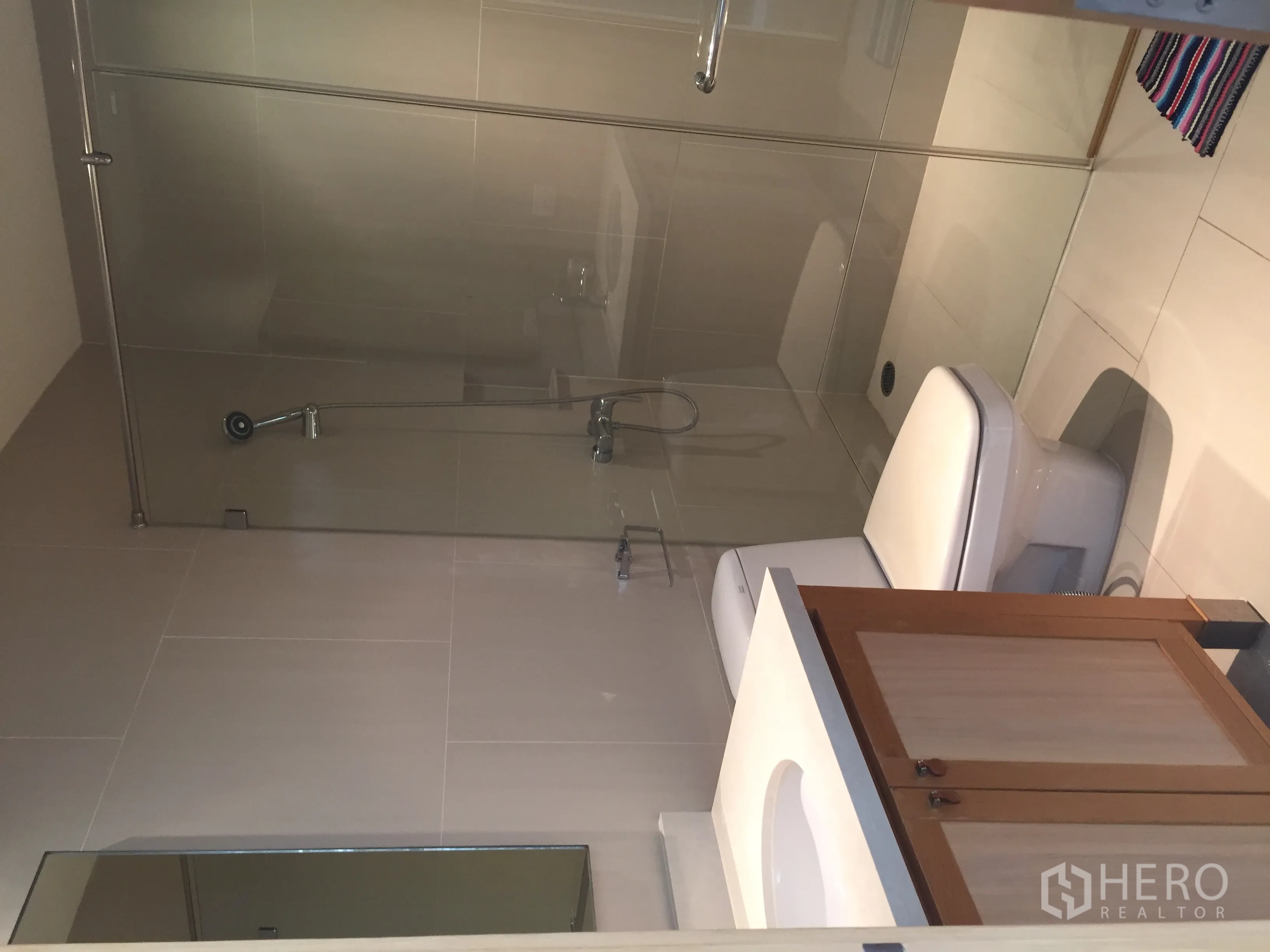Condominium for rent or sale in Khlong Toei, Bangkok - Contemporary bathroom with glass-enclosed shower, toilet and vanity.