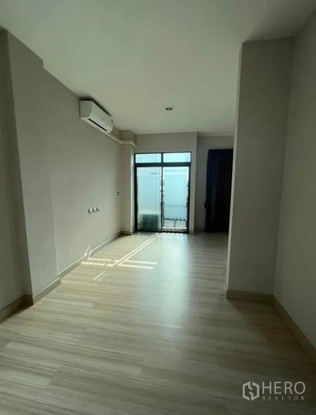 Townhouse for rent or sale in Bang Kho Laem, Bangkok - Upper-floor landing with air conditioner and glass door leading to a small balcony.