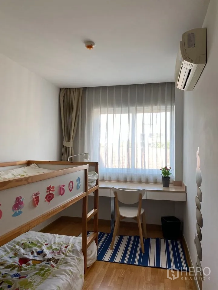 Condominium for rent or sale in Phra Khanong, Bangkok - Kids’ bedroom with wooden bunk bed, study desk and striped rug by a sunny window.