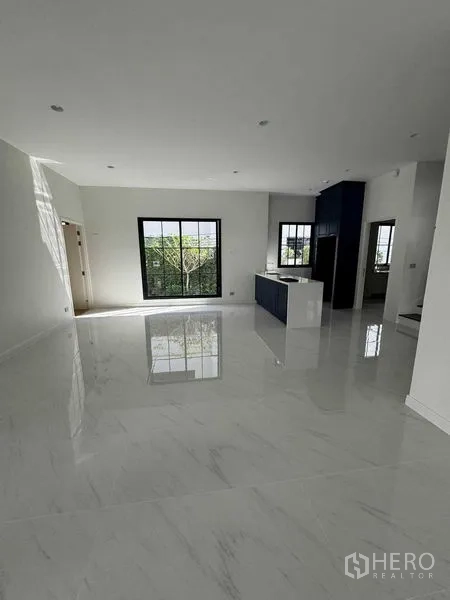 Detached House for rent in Bang Khen, Bangkok - Bright open-plan living area with glossy marble-look floors, large windows and a modern island kitchen.