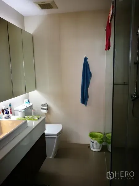 Condominium for rent or sale in Watthana, Bangkok - Modern bathroom with glass shower, wall-mounted vanity and toilet.