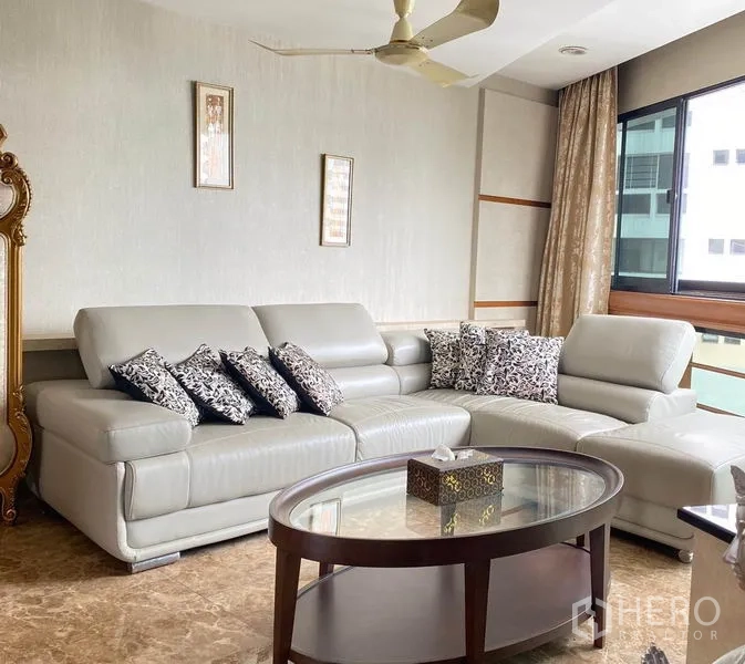 Condominium for rent in Khlong Toei, Bangkok - Bright lounge corner with L-shaped leather sofa, ceiling fan and large window.