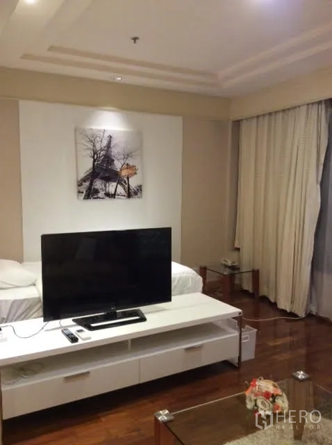 คอนโด ให้เช่าในPathum Wan, Bangkok - ห้องนั่งเล่นอบอุ่น ทีวีจอใหญ่บนตู้สีขาว ภาพแขวนผนัง และผ้าม่านสูง