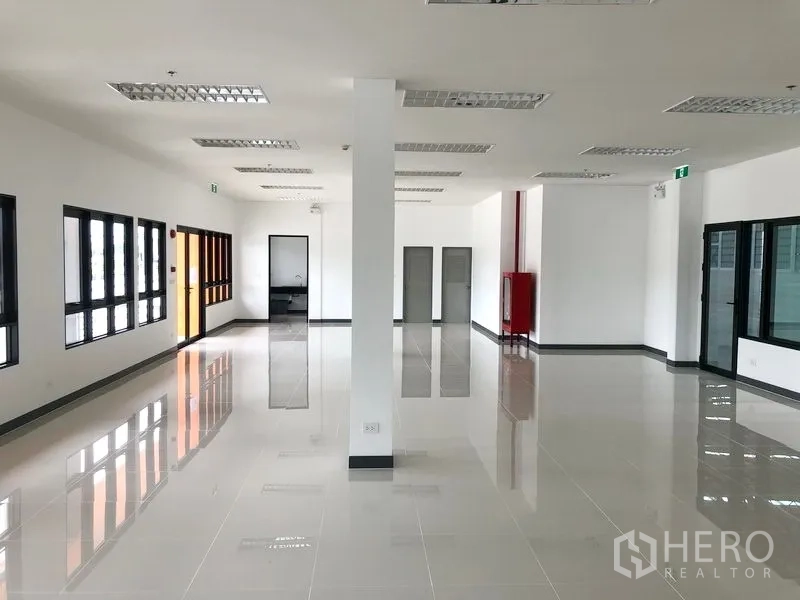 Factory for rent in Wang Noi, Phra Nakhon Si Ayutthaya - Bright office space with tiled flooring, grid ceiling lights, and large black-framed windows.