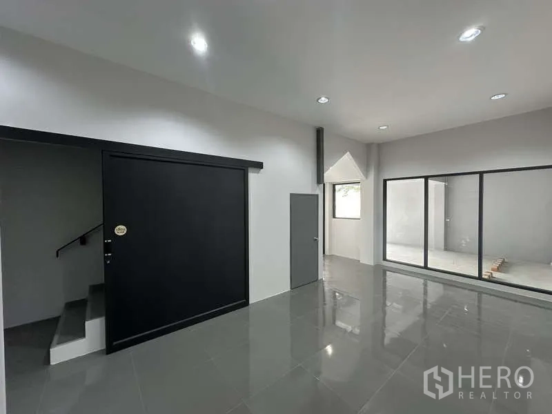 Factory for rent or sale in Bang Bua Thong, Nonthaburi - Ground-floor office with black sliding door and access to a small courtyard.