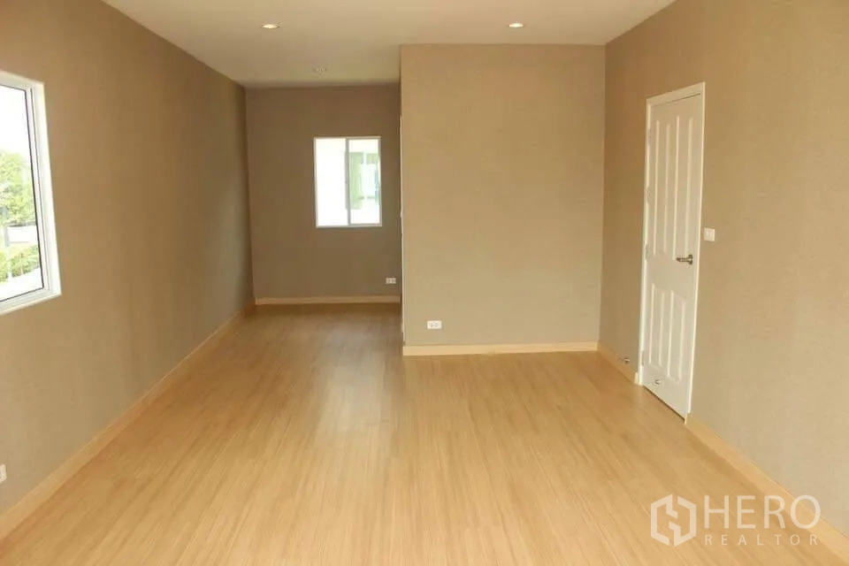 Detached House for rent in Saphan Sung, Bangkok - Long upstairs room with warm wood flooring, recessed lights and a white door.