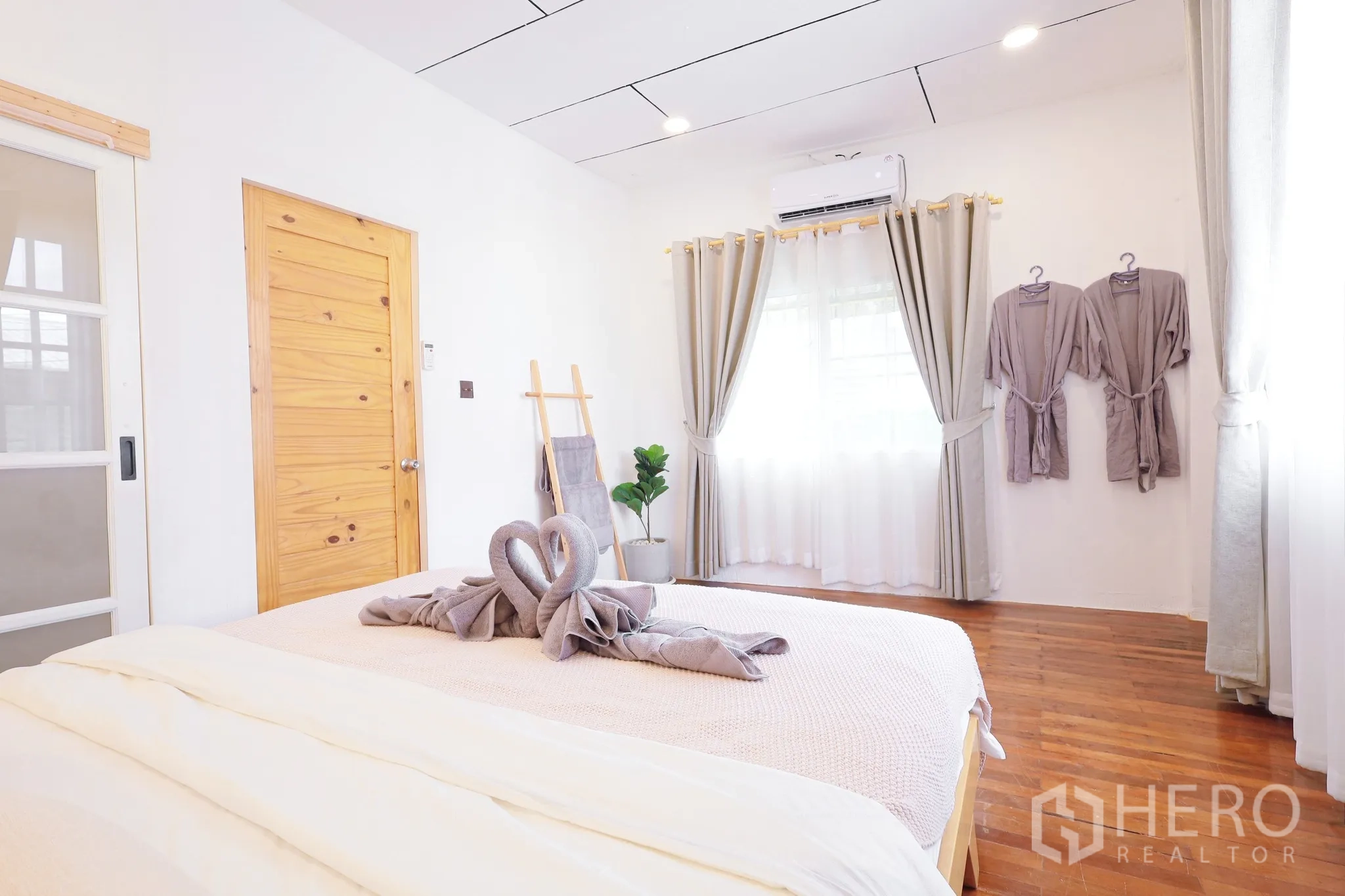 Townhouse for rent in Din Daeng, Bangkok - Sunlit bedroom with bed, wall robes, air-conditioning, wooden door and soft curtains.