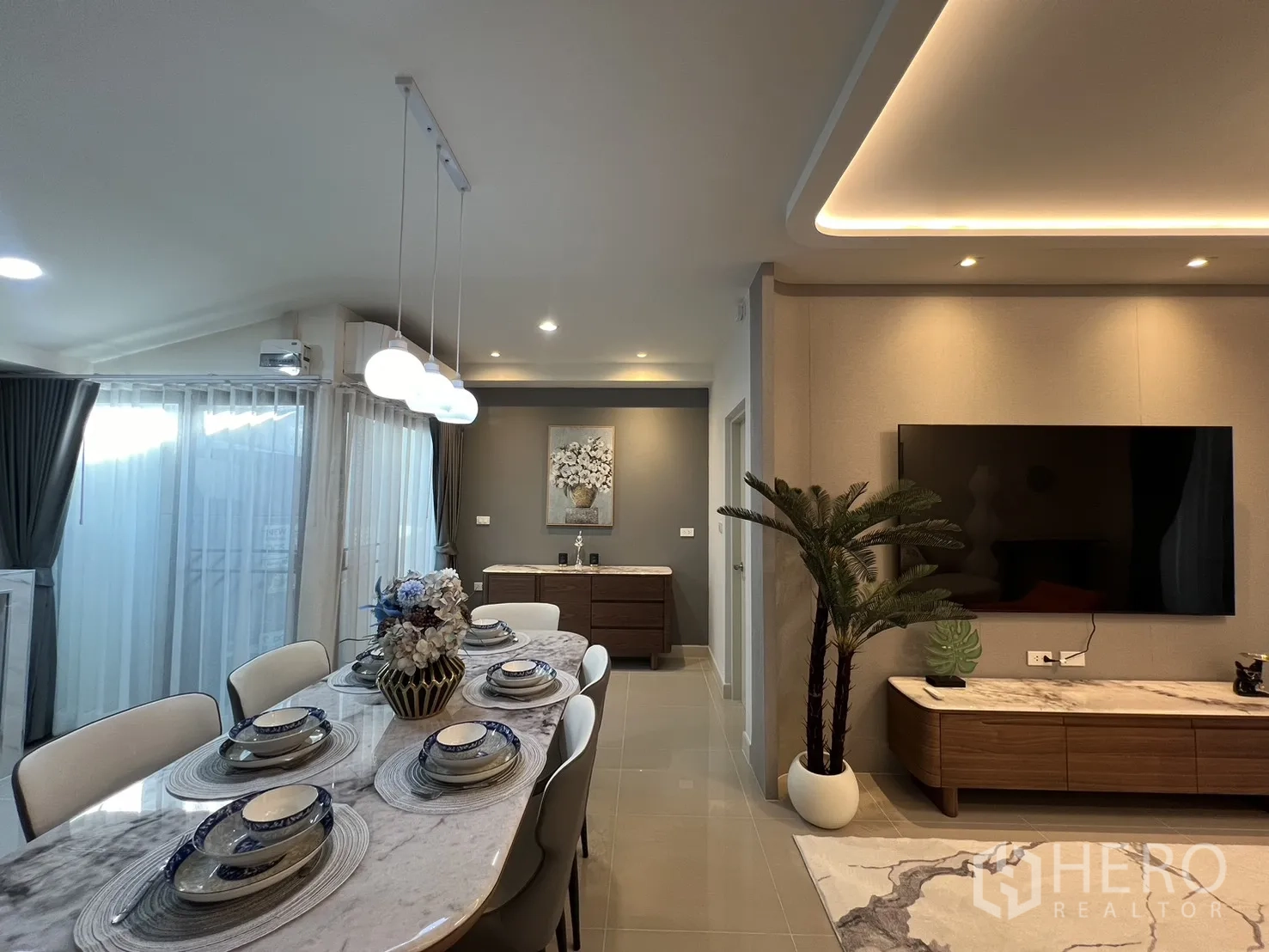 联排别墅 for rent in Bang Phli, Samut Prakan - 餐桌旁是电视柜与绿植，暖色灯光营造氛围。
