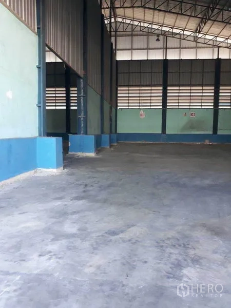 Factory for rent in Samut Prakan - Spacious factory interior with high steel truss roof and smooth concrete floor.