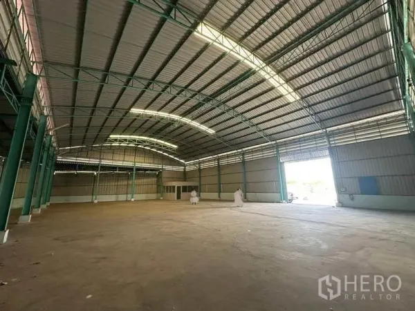 Warehouse for rent in Phra Nakhon Si Ayutthaya - Spacious warehouse interior with high curved steel roof, green columns, and a wide loading entrance.