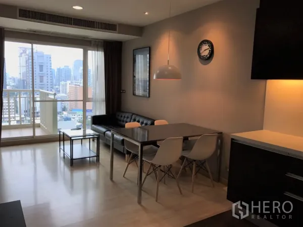 Condominium for rent in Watthana, Bangkok - Bright living and dining area of a 2-bed condo in Watthana, Bangkok with balcony and city skyline view.