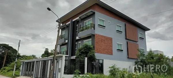 Townhouse for rent or sale in Saphan Sung, Bangkok - Modern three-storey townhouse exterior with balconies, brick accents and privacy screens.