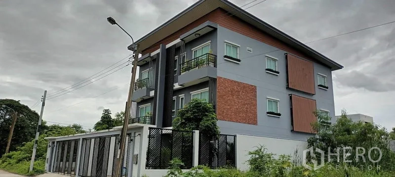 Townhouse for rent or sale in Saphan Sung, Bangkok - Modern three-storey townhouse exterior with balconies, brick accents and privacy screens.