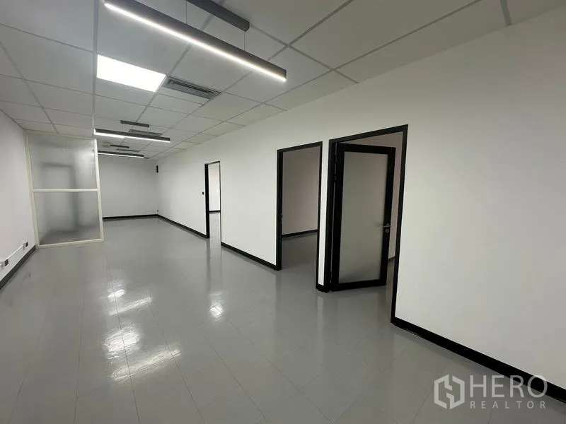 Office Space for rent - Work area with open doors to private rooms and linear LED lights.