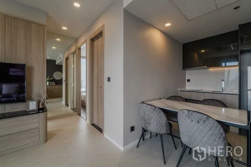 Condominium for rent in Pathum Wan, Bangkok - Open-plan dining space and compact kitchen with glossy upper cabinets and refrigerator.