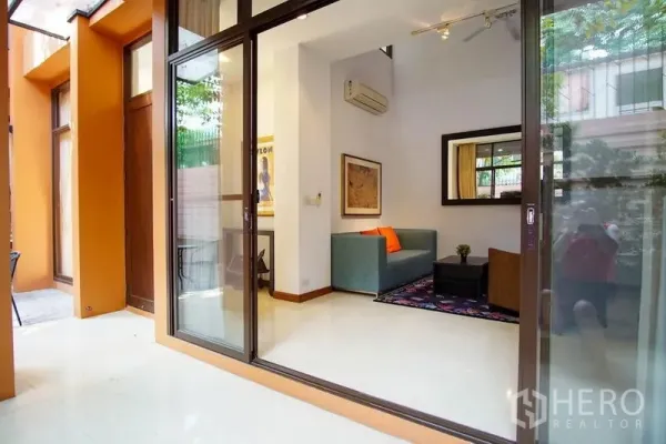 ทาวน์เฮาส์ ให้เช่าในWatthana, Bangkok - ประตูกระจกบานเลื่อนเปิดสู่ห้องนั่งเล่นสว่างพร้อมโซฟาและกระจกบานใหญ่