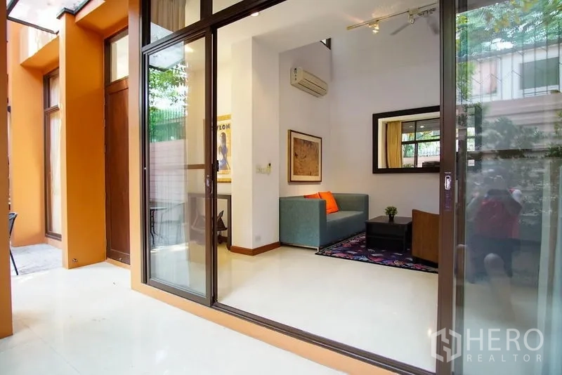 ทาวน์เฮาส์ ให้เช่าในWatthana, Bangkok - ประตูกระจกบานเลื่อนเปิดสู่ห้องนั่งเล่นสว่างพร้อมโซฟาและกระจกบานใหญ่