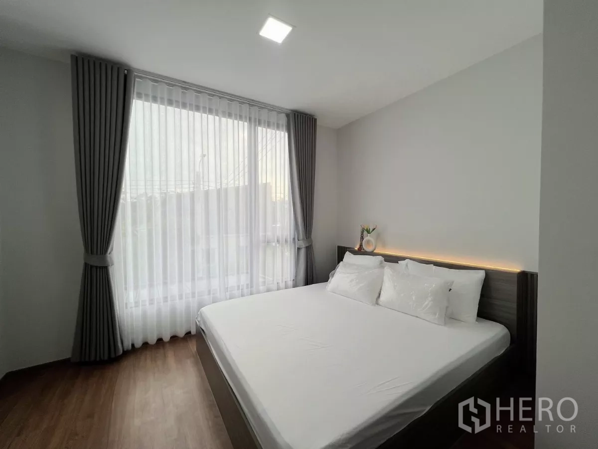 Townhouse for rent in Bang Phli, Samut Prakan - Sunlit master bedroom with king bed, sheer curtains and warm wood flooring.
