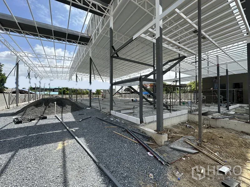 Warehouse for rent in Lat Krabang, Bangkok - Interior view of the new warehouse structure showing columns, roof panels and gravel base ready for flooring.