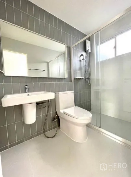 联排别墅 for rent in Prawet, Bangkok - 浴室设玻璃淋浴房、坐便器、台盆与大镜子。