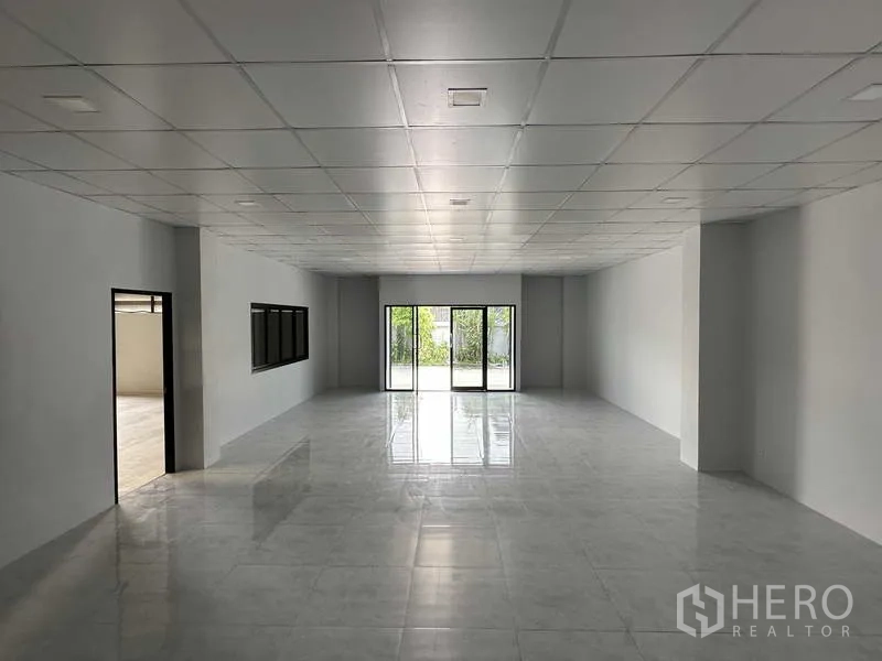 Warehouse for rent in Bang Phli, Samut Prakan - Bright office space with glossy tiles and glass sliding doors opening to exterior greenery.