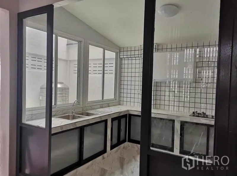 Townhouse for rent or sale in Din Daeng, Bangkok - Kitchen angle showing double sink by the windows and glass partition doors.