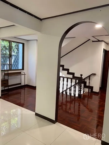 联排别墅 出租在Khlong Toei, Bangkok - 楼梯厅带拱形门洞、木楼梯、窗户与亮泽木地板。