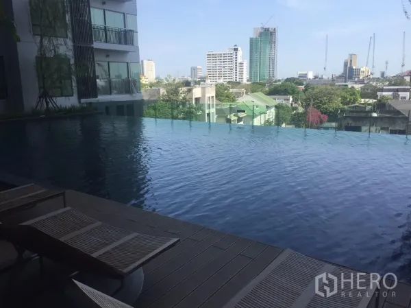 Condominium for rent in Khlong Toei, Bangkok - Rooftop infinity swimming pool with sun loungers and Bangkok city views.