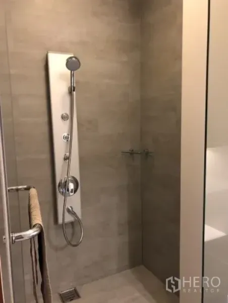 Condominium for rent or sale in Khlong Toei, Bangkok - Modern bathroom featuring a glass-enclosed shower and multi-function shower panel.