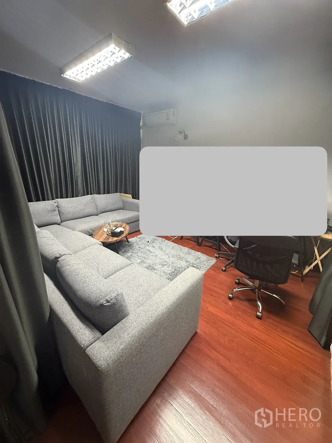 家庭办公室 for rent in Watthana, Bangkok - 影音式会议室，灰色转角沙发、深色窗帘、明亮顶灯与地毯。