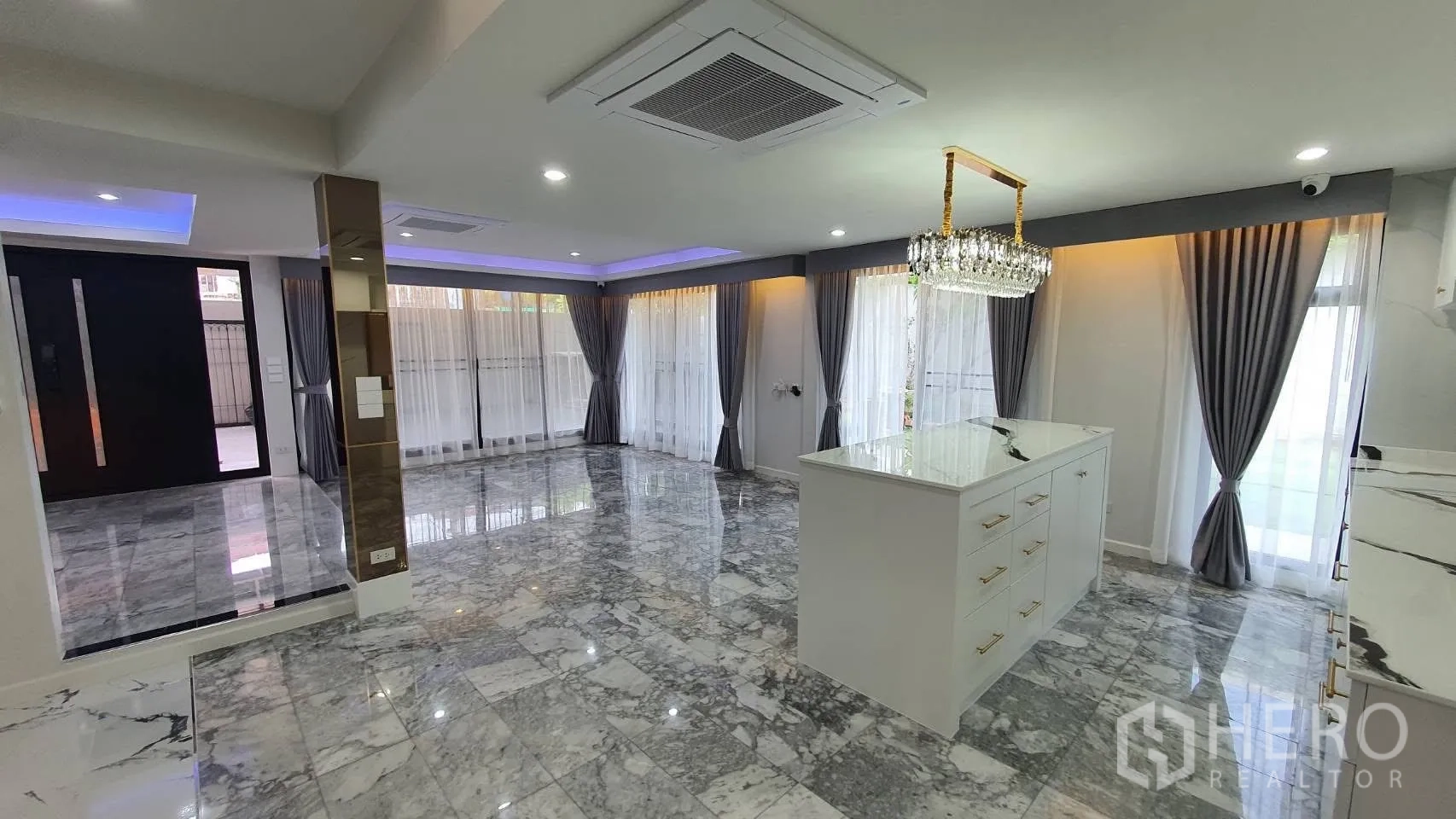 Detached House for rent in Lat Phrao, Bangkok - Open-plan living area with marble floors, island and full-height curtains.