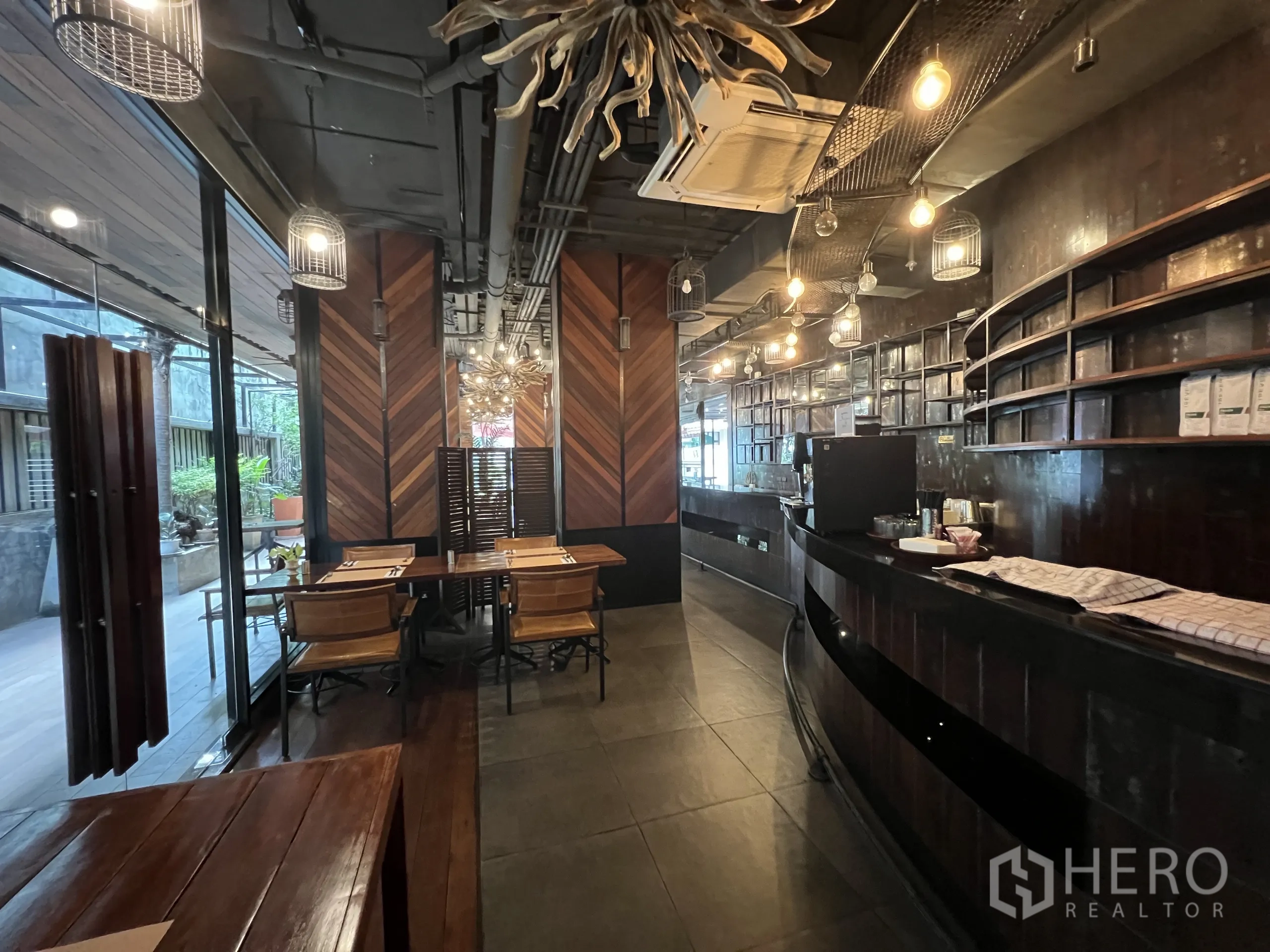Retail Space for rent in Watthana, Bangkok - Curved bar counter with shelving, tables and chairs, and glass doors to the terrace.