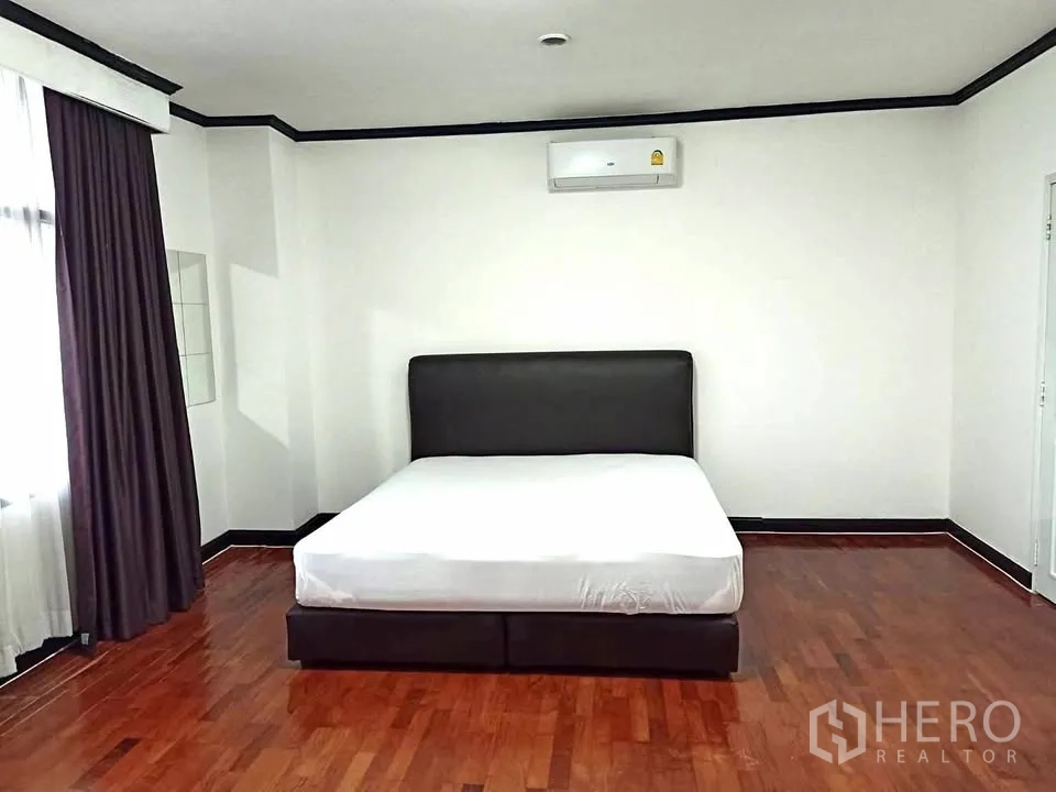 Condominium for rent in Watthana, Bangkok - Large bedroom with double bed, air-conditioning, curtains, and wood floors.