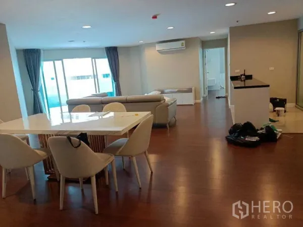 คอนโด ให้เช่าหรือขายในHuai Khwang, Bangkok - ห้องนั่งเล่นกว้างพร้อมหน้าต่างสูงจรดเพดาน ชุดทานอาหาร และเคาน์เตอร์ครัว.