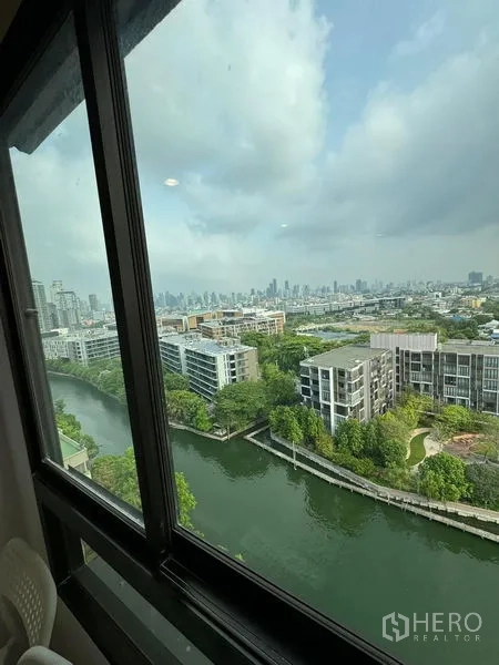 Condominium for rent or sale - High-floor window view over a canal, green space, and Bangkok skyline.