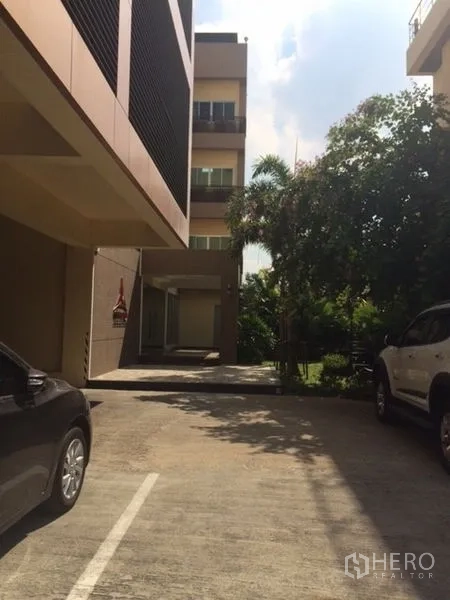 带办公室的家 出售在Phra Khanong, Bangkok - 建筑之间的私家车道与停车区，周围绿树成荫。