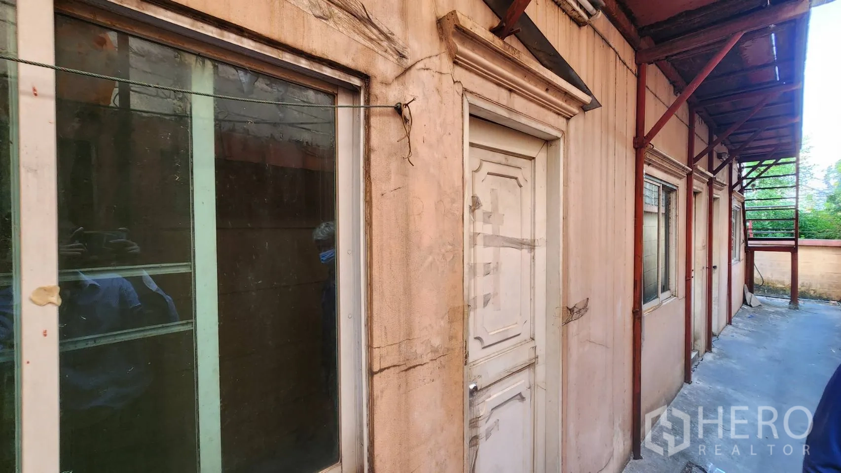 Warehouse for rent in Nonthaburi - Exterior side walkway with small rooms and doors along the building.