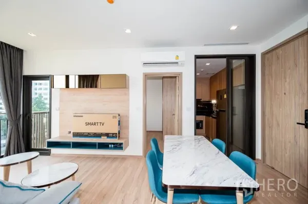 Condominium for rent in Watthana, Bangkok - TV wall and dining space facing the balcony, with a sliding door to the separate kitchen.
