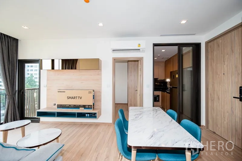 Condominium for rent in Watthana, Bangkok - TV wall and dining space facing the balcony, with a sliding door to the separate kitchen.