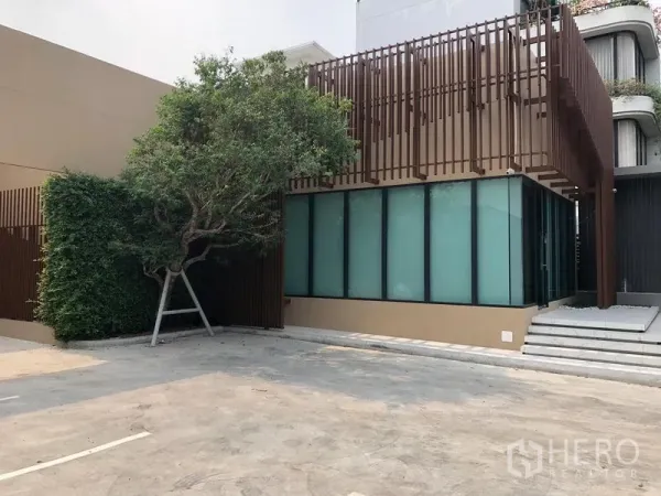 Retail Space for rent in Watthana, Bangkok - Modern low-rise retail building with frosted glass facade, vertical slatted screens and a large forecourt parking area in Watthana, Bangkok.