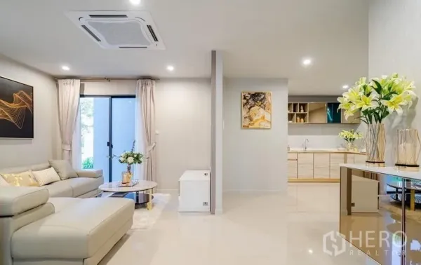 Detached House for sale in Lam Luk Ka, Pathum Thani - Bright open-plan living room with L-shaped sofa and sliding glass door next to the kitchen.