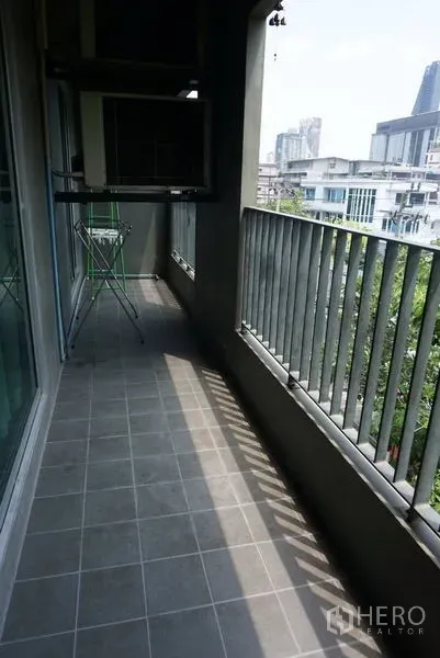 Condominium for sale in Khlong Toei, Bangkok - Long covered balcony with tiled floor and metal railings, ideal for outdoor seating.