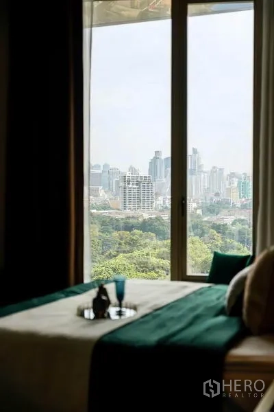 公寓 出租或出售在Bang Rak, Bangkok - 卧室窗景，俯瞰曼谷天际线与大片公园绿意。