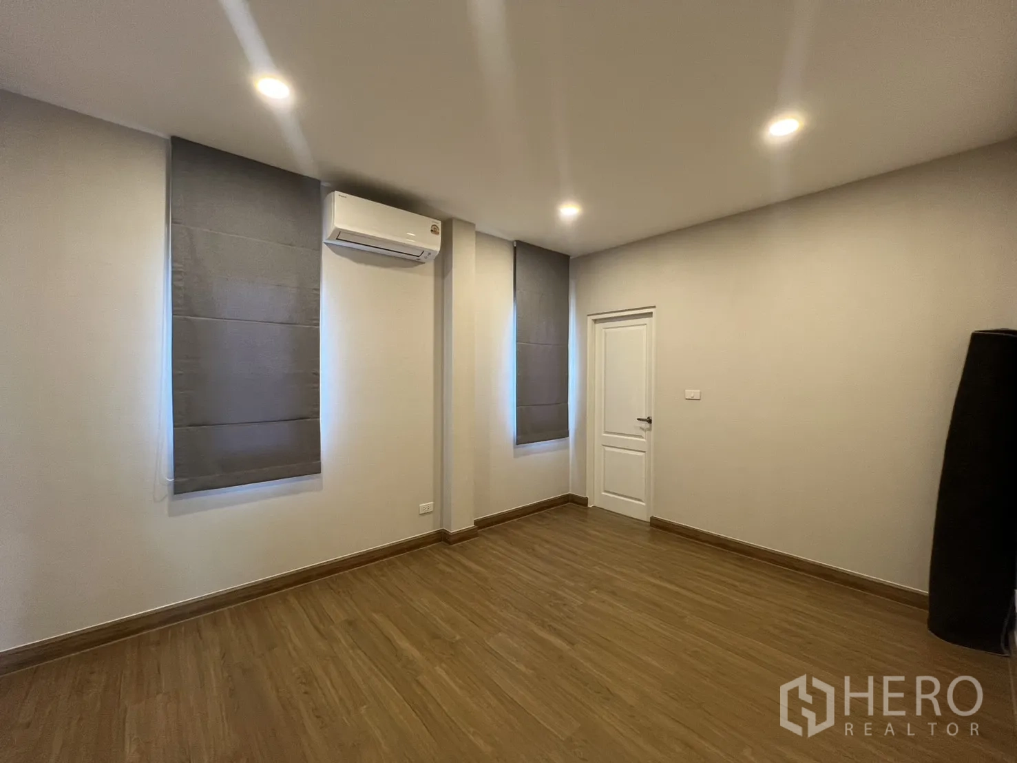 独栋房屋 for rent in Lat Krabang, Bangkok - 卧室一角，双窗帘、木地板与白色房门。