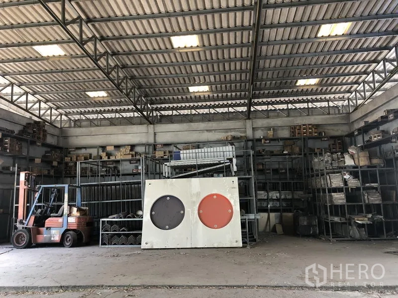 Warehouse for rent or sale in Lam Luk Ka, Pathum Thani - Warehouse interior with shelving, a forklift, and metal roof trusses.